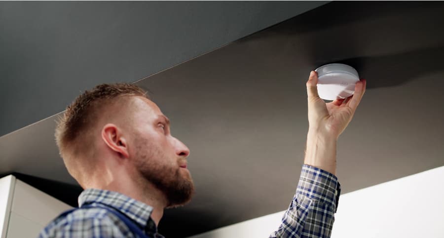 Man connecting a smoke detector on ceiling of home